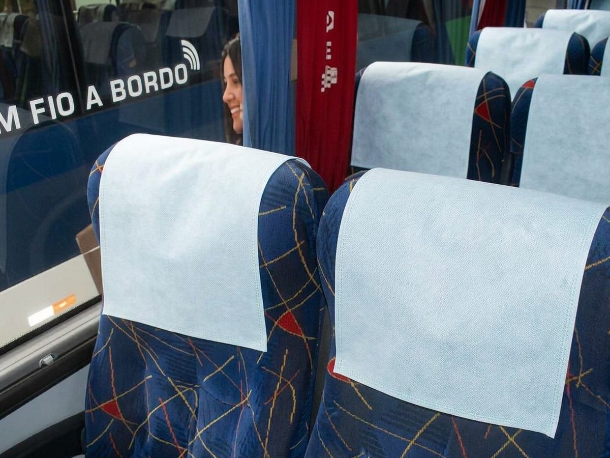 Cabeceiras em TNT azul-claro sobre poltronas de ônibus rodoviário