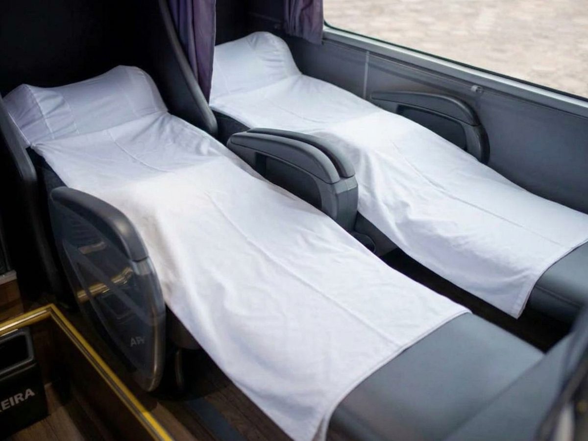 Lençóis brancos sobre poltronas leito de ônibus rodoviário